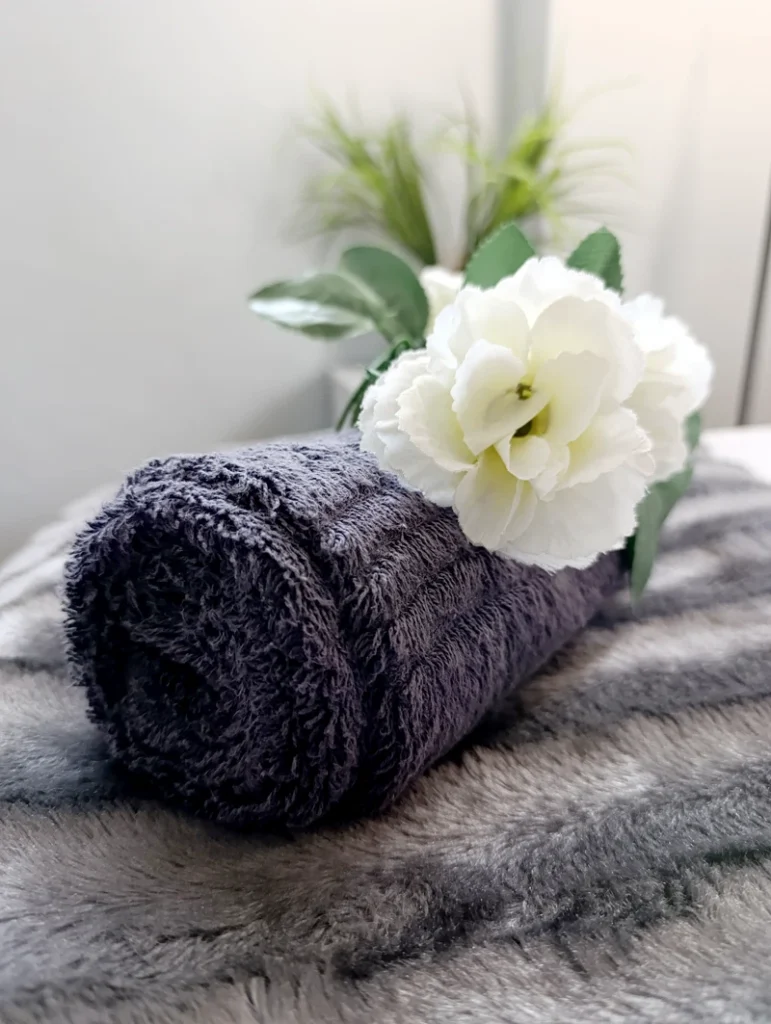Rolled towel and floral decor in the massage suite at Absolute Beauty, Brackenfell – creating a peaceful space for skin treatments.